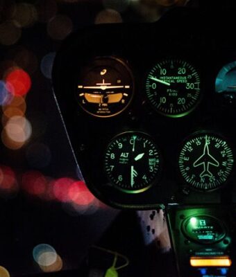 Illuminated dashboard dials of a vehicle cockpit at night.