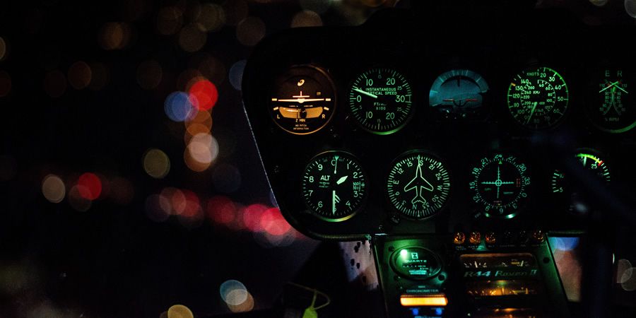 Illuminated dashboard dials of a vehicle cockpit at night.
